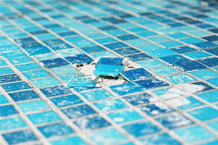 Primer plano del gresite de una piscina con teselas sueltas y las juntas deterioradas